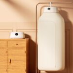 Compact hanging electric clothes dryer machine with collapsible cream fabric dry bag, hanging hook, and digital smart touch control panel.